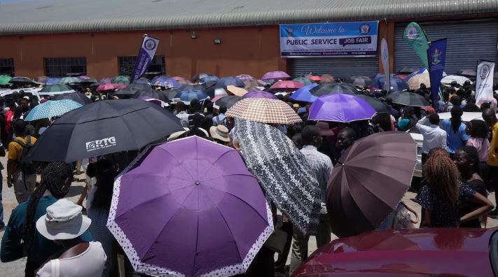 Young people wait outside the entrance to a government job fair, in Harare, Wednesday, Dec. 6, 2023