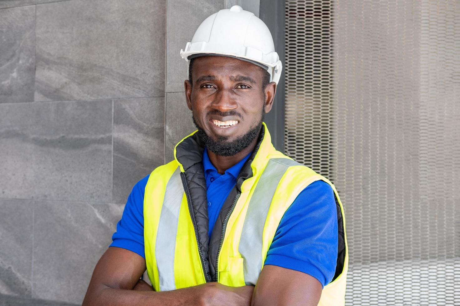 selective focus at face of black african foreman at building construction site wearing protective hat and safety equipment smile and feeling happy at work civil engineer working free photo